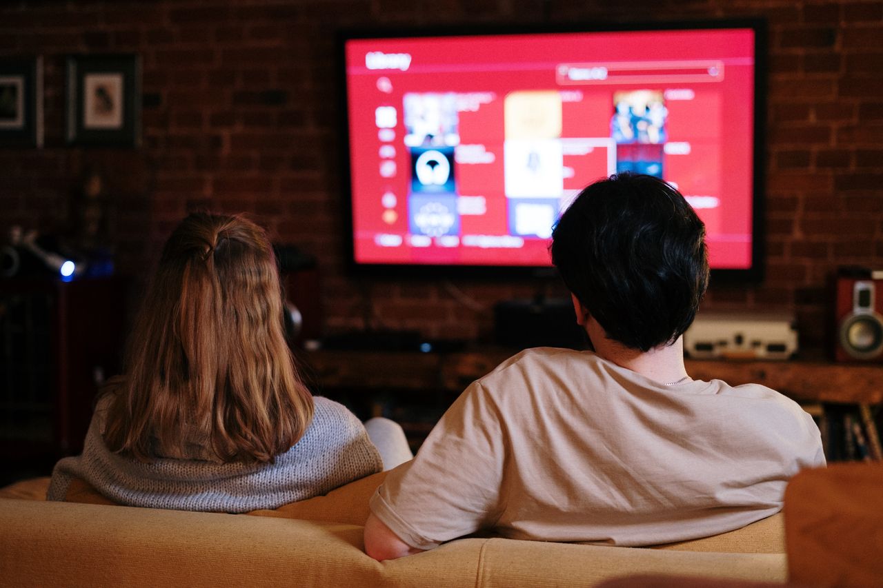 Mastering the First Impression: Your intriguing post title goes here A couple enjoys streaming shows on a large TV in a cozy, brick-walled living room.