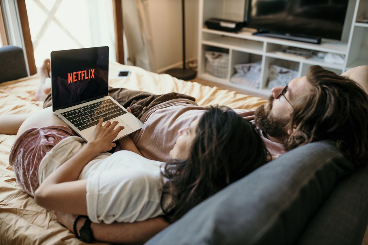 Crafting Captivating Headlines: Your awesome post title goes here A cozy couple lounging in bed, streaming Netflix together on a laptop, enjoying a peaceful moment.