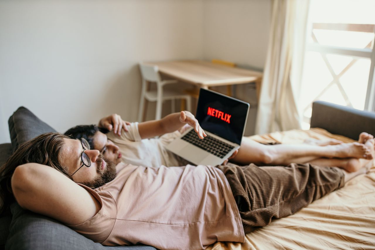 Services A couple lounging on bed watching Netflix, creating a cozy indoor atmosphere.